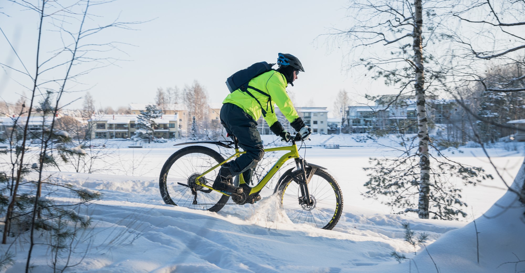 A biker in the snow. Houses in the background.