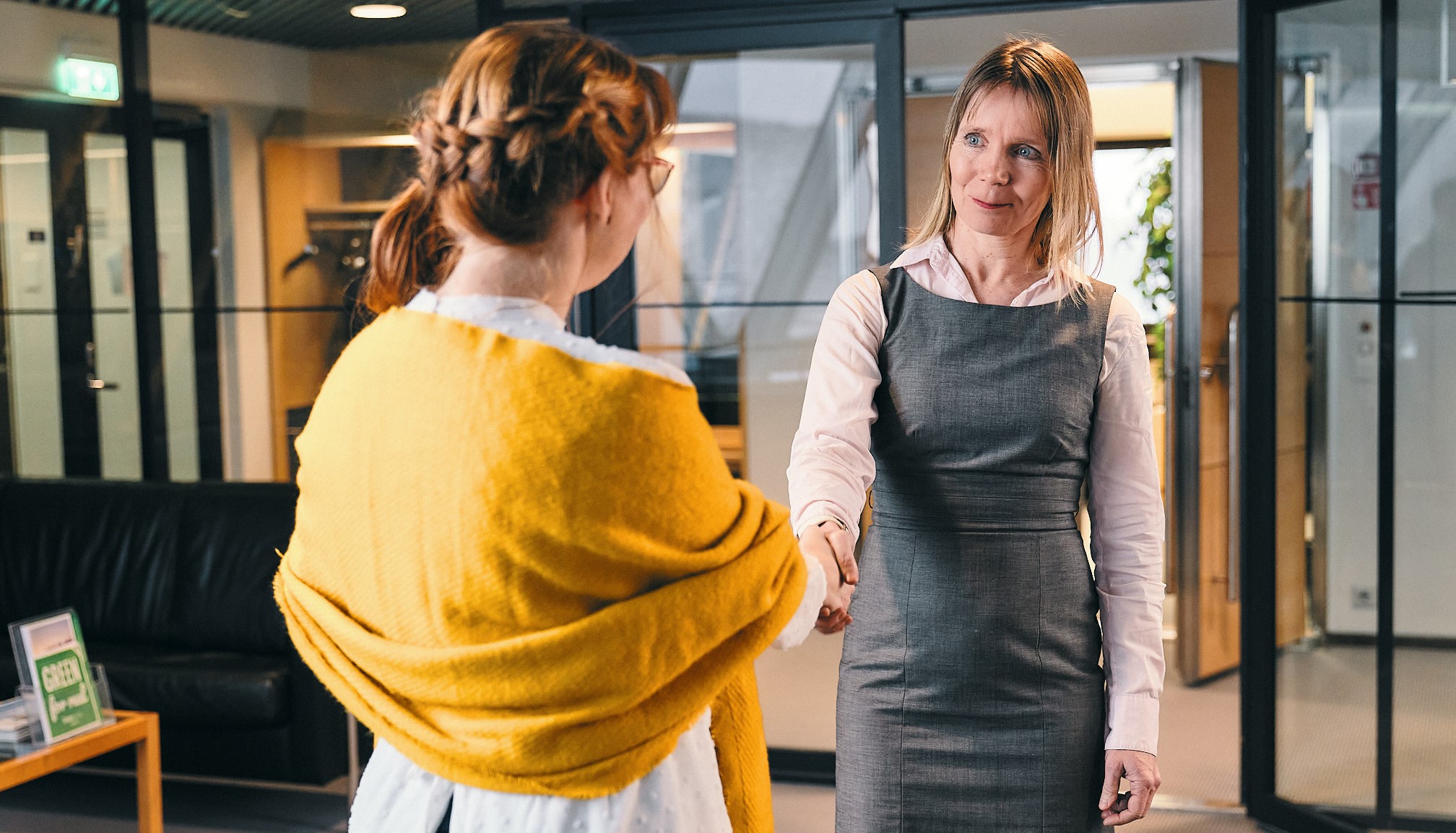 Two people shaking their hands in an office building.