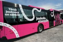 Pink electric bus, which has texts "Tässä Joukossa on sähköä" and "Kuljetaan Joukolla"